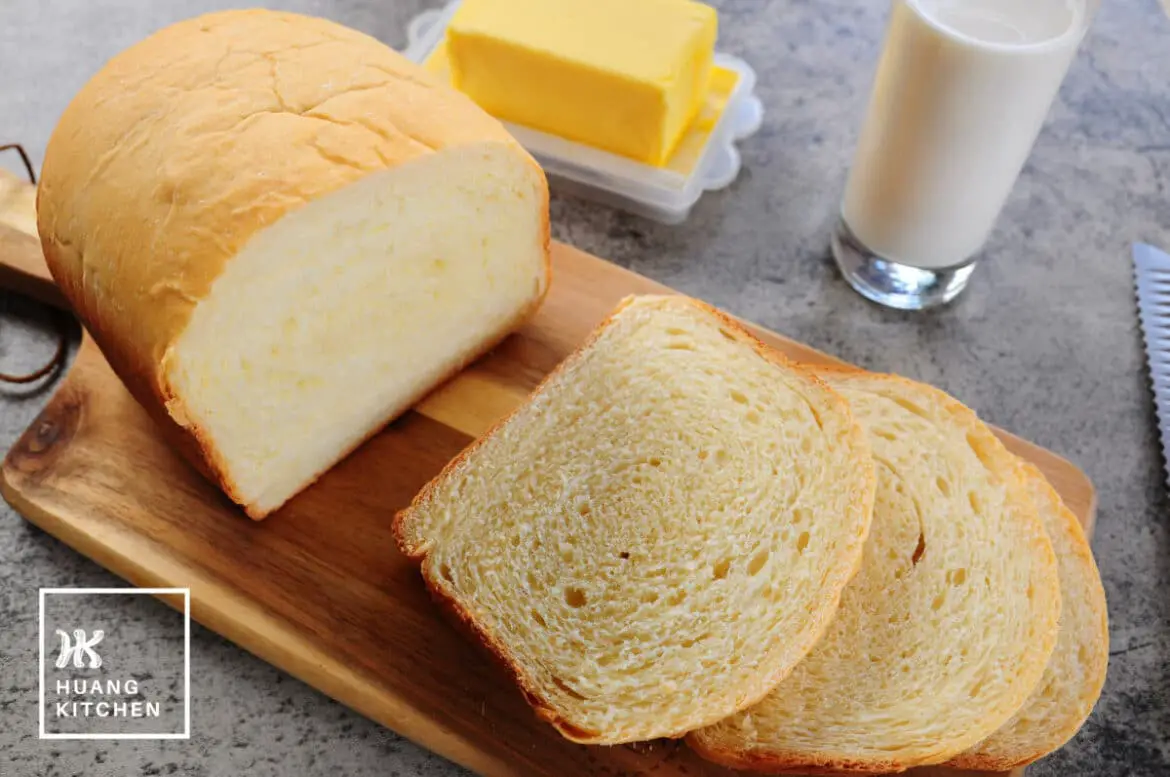 Basic White Bread Bread Machine Recipe by Huang Kitchen - top down view of bread slices on wooden board with milk and butter