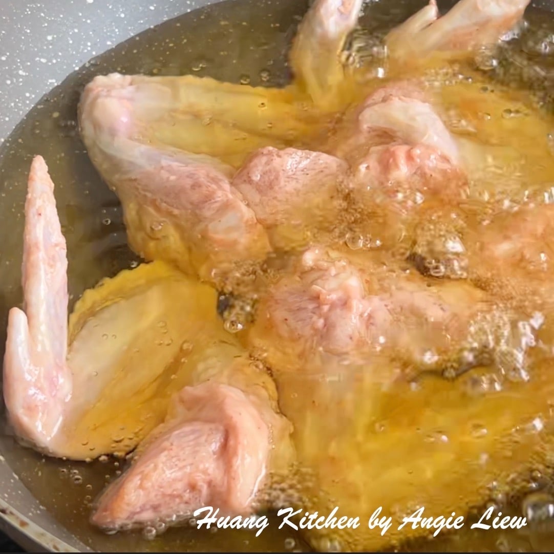 Place marinated chicken wings in hot oil, one at a time.